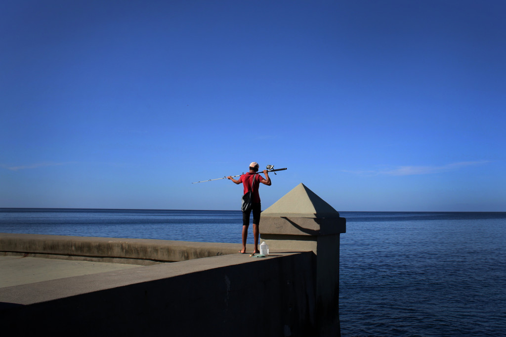 A fisherman stands on the Malecon, a seawall along the coast of Havana, Cuba.