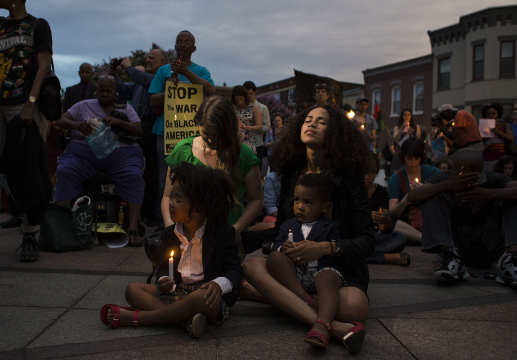 Maybelline McCoy, 30, of Washington, DC, sits in silence holding candles with her children Micah McCoy, 4, and Malakai McCoy, 2, as people gather in front of the African-American Civil War Memorial on U Street in Washington, DC, during a prayer vigil in remembrance of the victims killed in the shooting at the historic Emanuel AME Church in Charleston, SC, on Friday, June 19, 2015. The vigil was hosted jointly by the NAACP DC Branch and National Black United Front and over 300 individuals were in attendance.