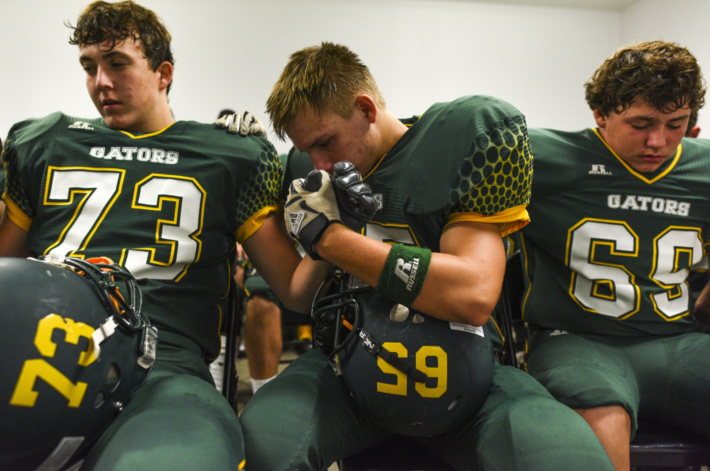 Greenwood Gators Cole Kremlin, number 73, left, Kevin Fields, number 65, and Jackson Fletecher, number 69, pray before taking the field against Logan County in a homecoming game at the Swamp on September 18, 2015 in Bowling Green, Kentucky. Fields was emotional due to the loss of his brother Kyle Fields, number 61, who committed suicide in May. MICHAEL NOBLE JR.