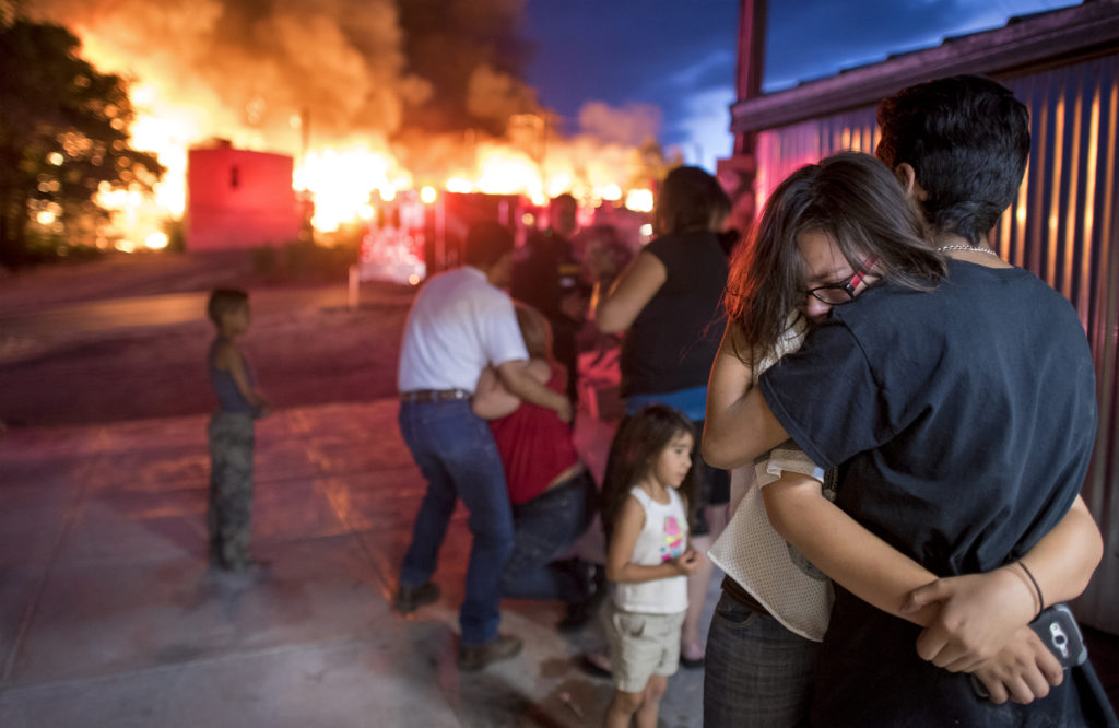 Inez Grace is held by her brother Leo Gomez as they watch their homes burn on Saturday June 26, 2016 in the Gamerco neighborhood on in Gallup, Nm.